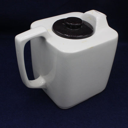 White ceramic pitcher with black lid on a dark background
