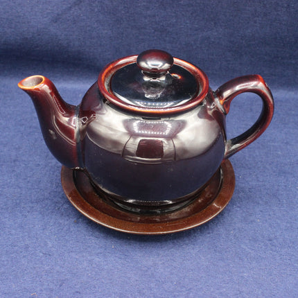 Ceramic teapot with a brown lid on a blue background