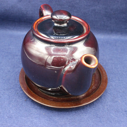 Ceramic teapot with a dark brown glaze on a blue background