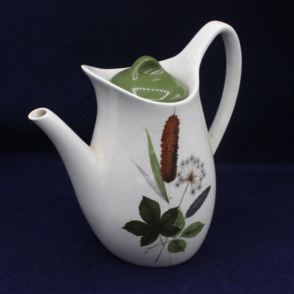 White teapot with botanical designs on a dark background