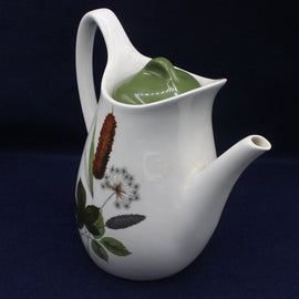White teapot with green lid and botanical designs on a dark background
