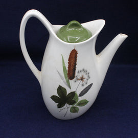 White teapot with nature-themed design on a dark background