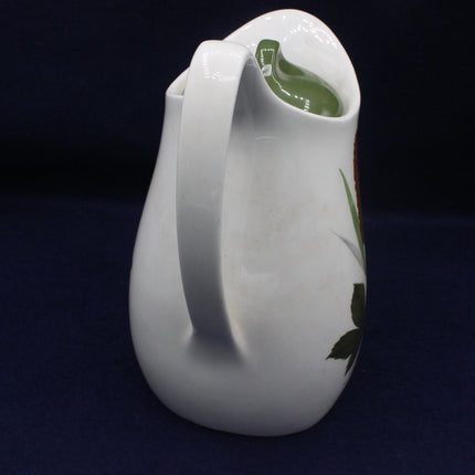 White ceramic pitcher with green accents on a dark background