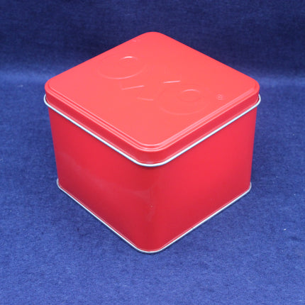 Red square tin box with a lid on a blue background
