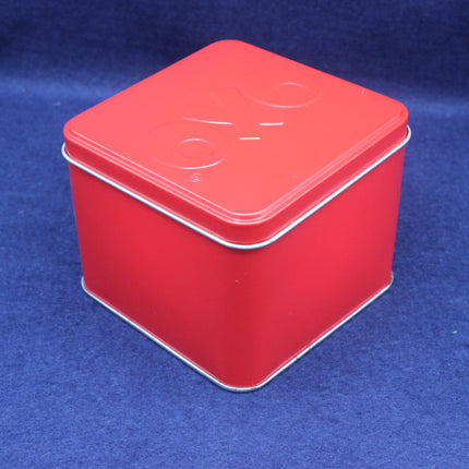 Red square tin box with a white lid on a blue background