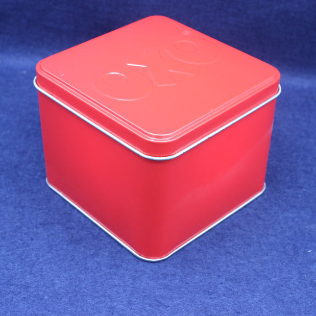 Red square tin box with a lid on a blue background