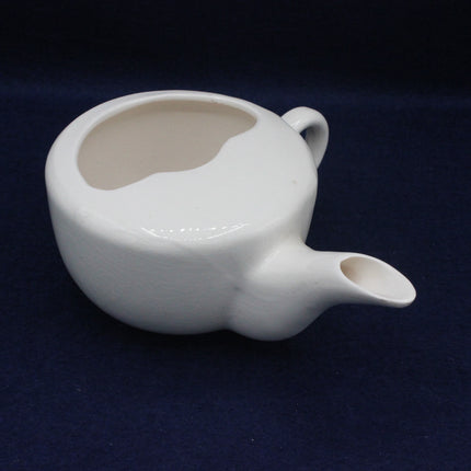 White ceramic teapot on a dark blue background