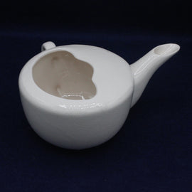 White ceramic teapot with a face design on a dark background