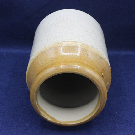 Cylindrical ceramic vase with two-tone glaze on a blue background