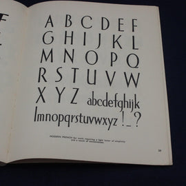 Open book displaying a typographic display of the alphabet on a white page.
