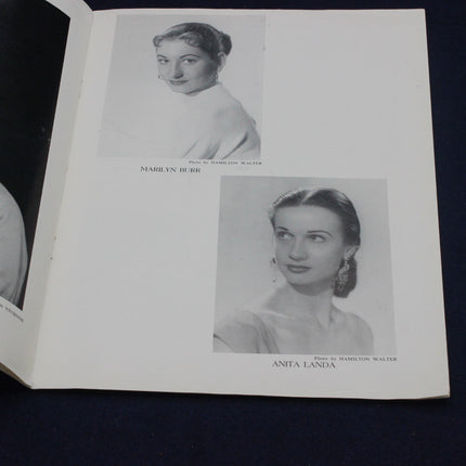 Book open to a page with black and white portraits of two women, Marilyn Burr and Anita Landa, on a dark background.