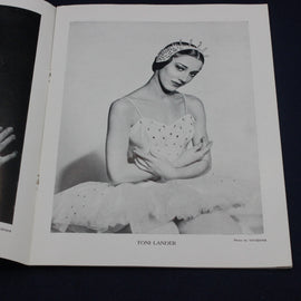 Black and white photograph of a ballerina in a tutu with a tiara, held in an open book.
