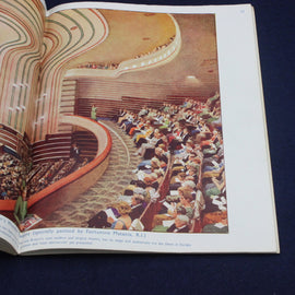 Illustration of a theater interior with audience members on a page from a book.