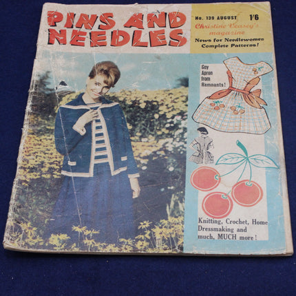 Vintage magazine cover of 'Pins and Needles' with a woman and sewing patterns on a blue background