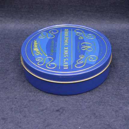 Blue round tin with gold text on a dark gray background