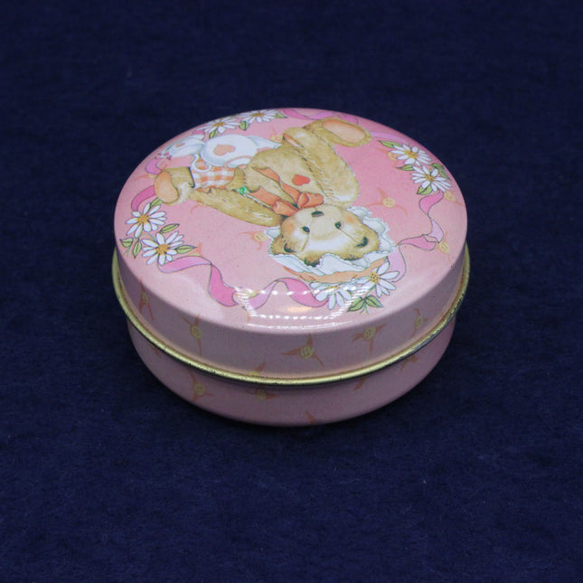 Pink round tin with teddy bear design on a dark blue background