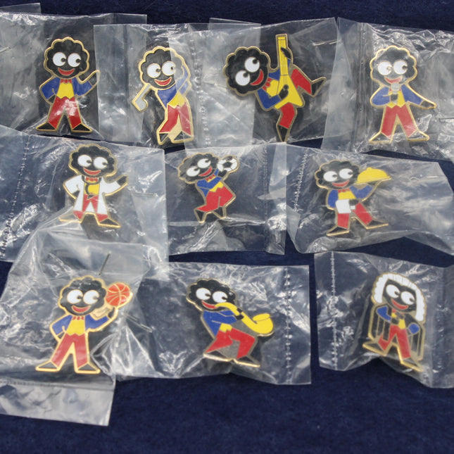 Collection of vintage Golliwog badges in clear packaging on a dark background