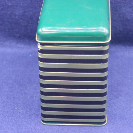 Rectangular tin with green top and blue and white striped sides on a blue background