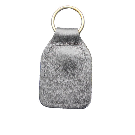 Gray leather key fob with gold ring on a blue textured background
