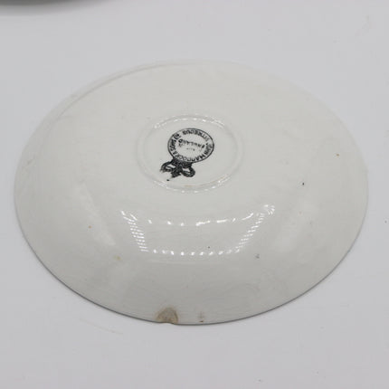 A white ceramic plate shown from the back, featuring a small black printed circular logo in the center.