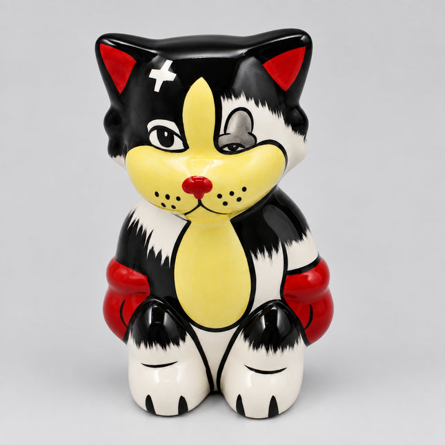 A ceramic cat figurine with a black, white, and yellow color scheme, featuring a red nose, red inner ears, and red cuffs, shown against a plain light gray background.
