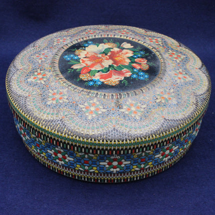 Decorative round tin with floral design on a blue background