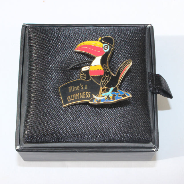 Colorful toucan pin with 'Mines a GUINNESS' text on a black box
