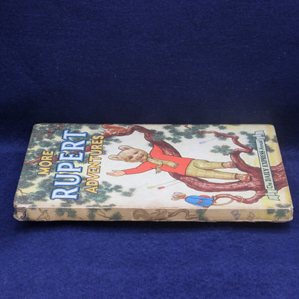 Book titled 'More Rupert Adventures' with a colorful cover featuring a bear character on a blue background
