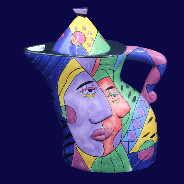 Colorful ceramic teapot with artistic face design on a blue background
