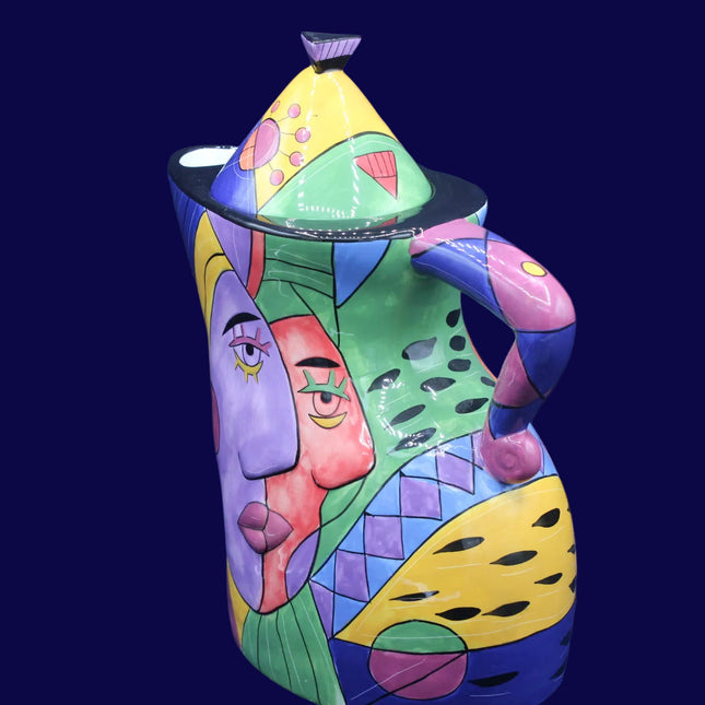 Colorful ceramic pitcher with abstract face design on a blue background