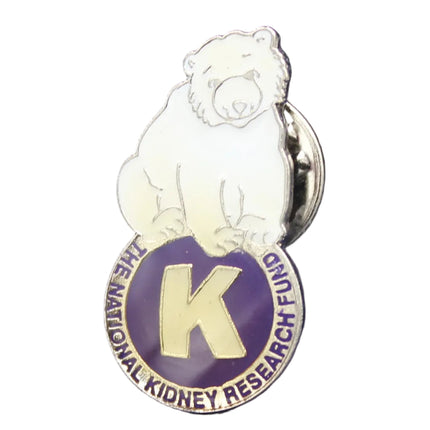 Pin with a bear design and 'K' logo on a dark blue background