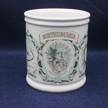 White mug with decorative design and 'Northumbria' text on a blue background