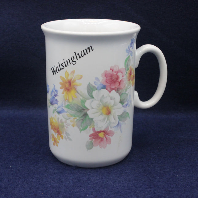 White mug with floral design and 'Walsingham' text on a dark blue background