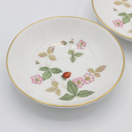 A white ceramic bowl with a delicate gold rim and a hand-painted strawberry and pink flower pattern, shown on a clean white background with another bowl partially visible in the upper right.