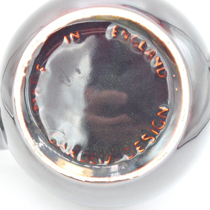 Close-up of the circular base of a glossy glass product, showing embossed text reading 'MADE IN ENGLAND' and 'CARDEW DESIGN' on a white background.