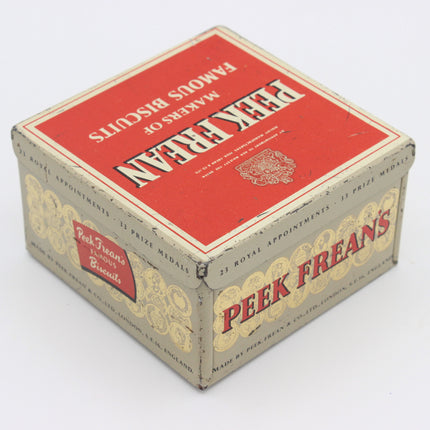Vintage Peek Freean Famous Biscuits tin box, showing the red top lid and patterned beige sides on a white background.