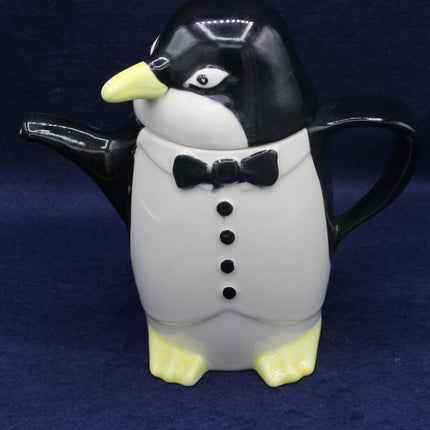 Penguin-shaped teapot with a bow tie on a dark blue background