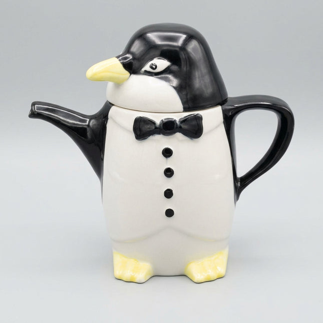 Penguin-shaped teapot with a bow tie on a dark blue background