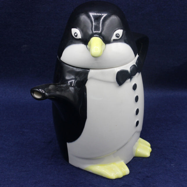 Penguin-shaped teapot with a bow tie on a blue background