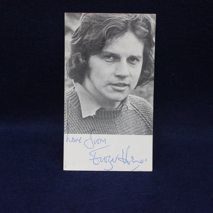 Black and white photo of Frazer Hines with an autograph on a dark background