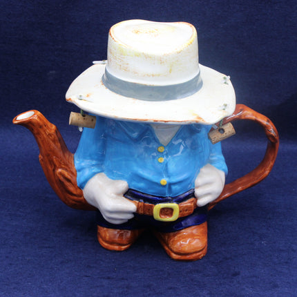 Teapot shaped like a Aussie figure with a blue shirt and white hat on a dark blue background