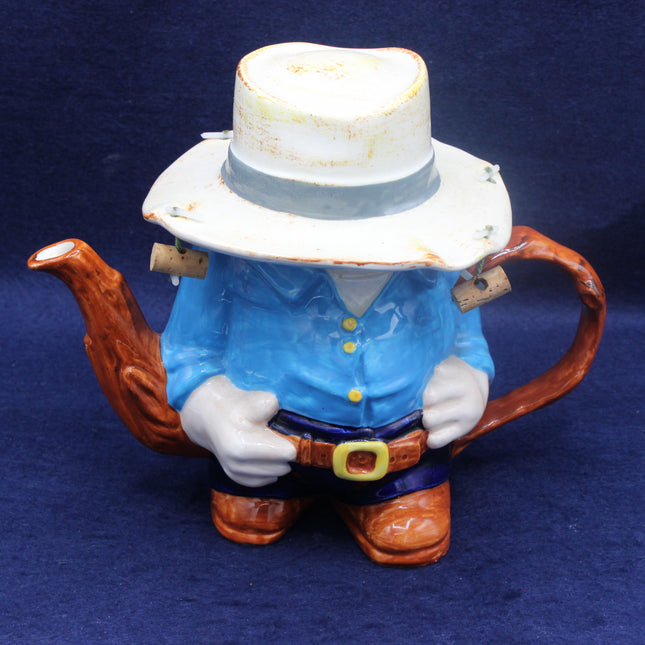 Teapot shaped like a Aussie figure with a blue shirt and white hat on a dark blue background