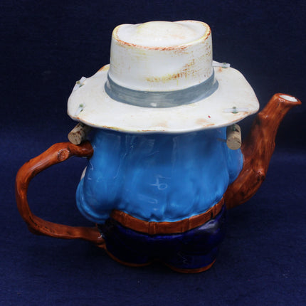 Teapot with swagman hat and boots on a dark blue background