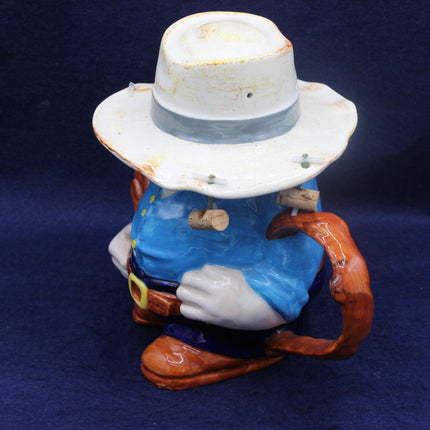 Ceramic Aussie figure with a white hat and blue shirt on a dark blue background