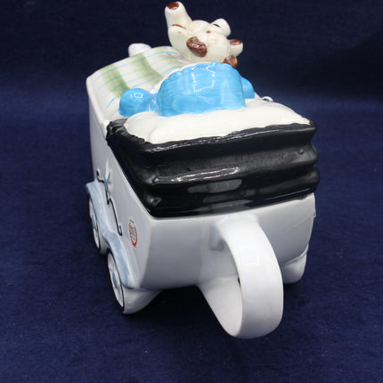 Ceramic toy of a dog in a car with a blue toy on a dark blue background