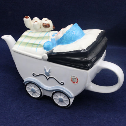 Ceramic teapot shaped like a baby carriage with a baby figure inside on a dark background