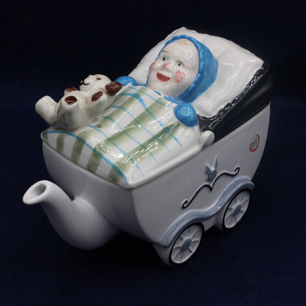 Teapot shaped like a baby in a crib with a clown face on a dark background