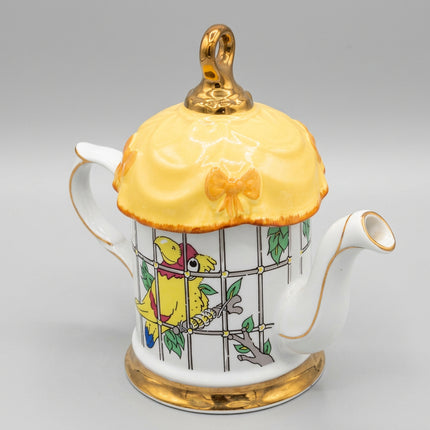 Decorative teapot with a yellow bird design on a dark blue background