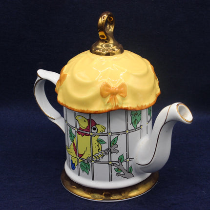 Decorative teapot with a yellow bird design on a dark blue background