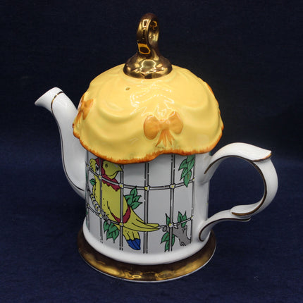 Teapot with a decorative birdcage lid featuring a yellow bird on a dark background